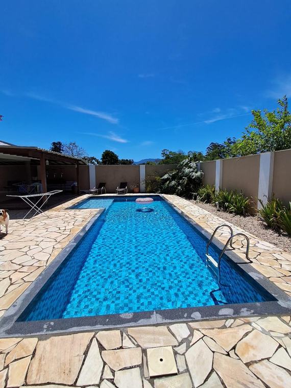 Piscina de alvenaria comprida com pastilha azul, água cristalina após limpeza
