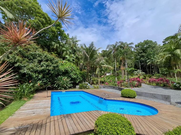 Piscina com deck de madeira em meio ao jardim, tratamento Guizoni Piscinas
