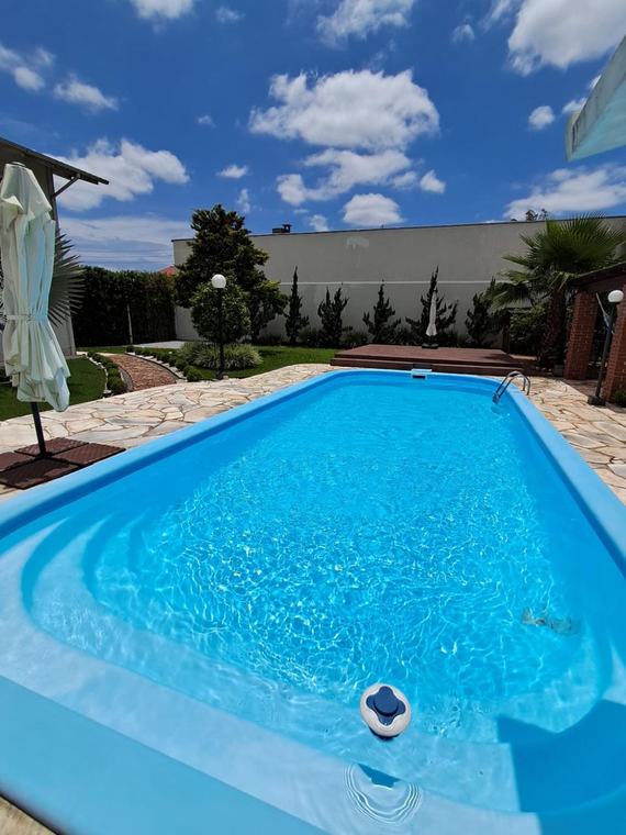 Piscina de fibra com prainha em área de jardim, água tratada pela Guizoni Piscinas